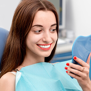 Woman examines cosmetically enhanced smile in mirror